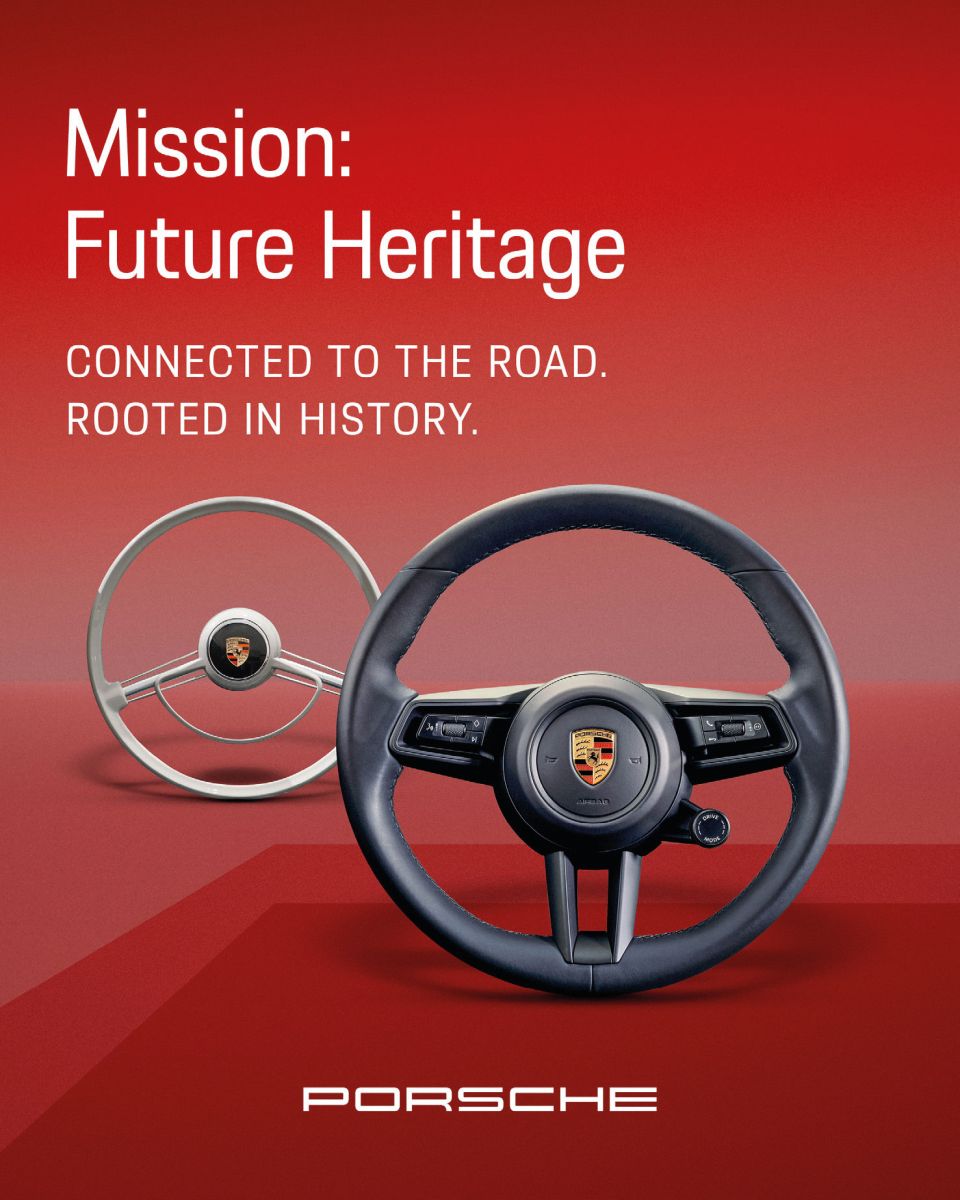 Auf rotem Hintergrund sind zwei Porsche-Lenkräder zu sehen, ein klassisches und ein modernes, mit dem Text: Mission: Future Heritage. Verbunden mit der Straße. Verwurzelt in der Geschichte. Das Porsche-Logo befindet sich am unteren Rand.